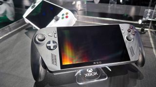 ASUS ROG Xbox Ally X (black) and ROG Xbox Ally (white) in a glass display case at Gamescom in August, 2025.