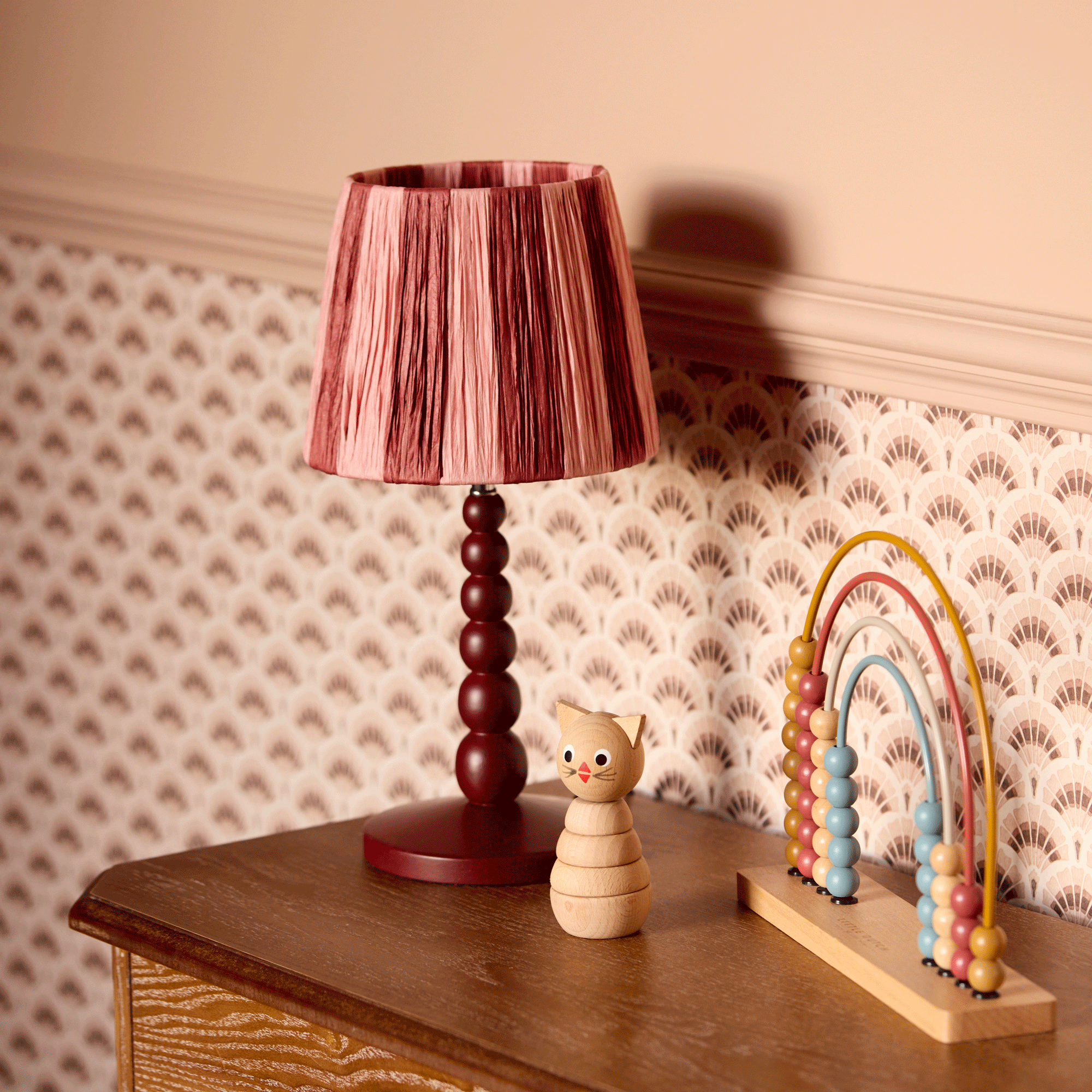 a bobble lamp with a striped raffia lampshade in a child's bedroom with painted walls and patterned wallpaper