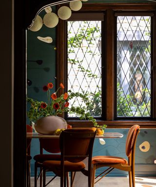 dining room with dark wooden accent, blue walls and wooden table and chairs with vase of red flowers