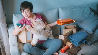 Woman with dog sat on her lap is opening up parcels 