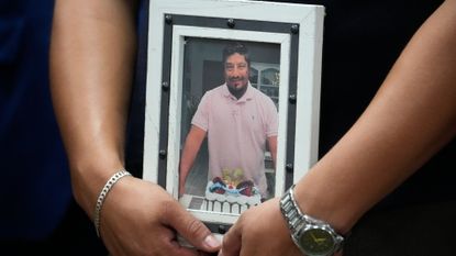 Ronaldo Salgado, son of Lorenzo Salgado Araujo, holds a photo of his father during a news conference about the ICE shooting death