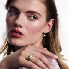 Young woman looking over her shoulder wearing silver earrings and diamond engagement ring.