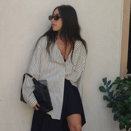 @laurencaruso_ wearing a striped button-down shirt and black skirt. 