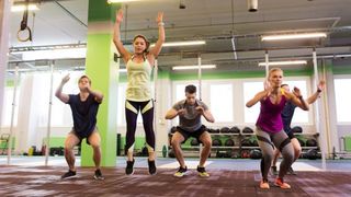 Group of people perform burpees in the gym