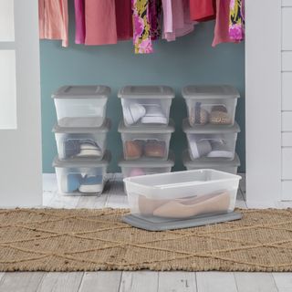 Clear plastic shoe storage boxes with gray lids in closet underneath clothes