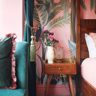 pink bedroom with palm wallpaper and bedside table