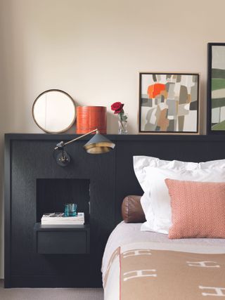 Built in headboard and storage in black with bed dressed in white and pink