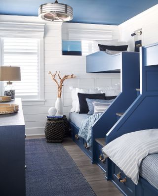 Blue bunkbeds with drawers and stairs in a blue and white coastal-inspired scheme illustrating bedroom ideas for boys.