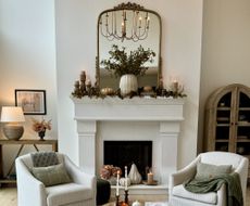 A living room with a fireplace decorated with pumpkins and tall candles