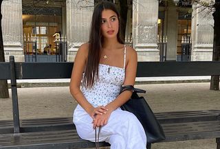 Tamara Mory wears a blue and white floral linen camisole with white linen pants in Paris.