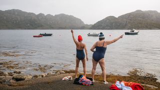 Swimmers in bobble hats on the shore of Torridon