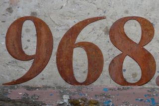 rusty metal numbers in front of brick wall
