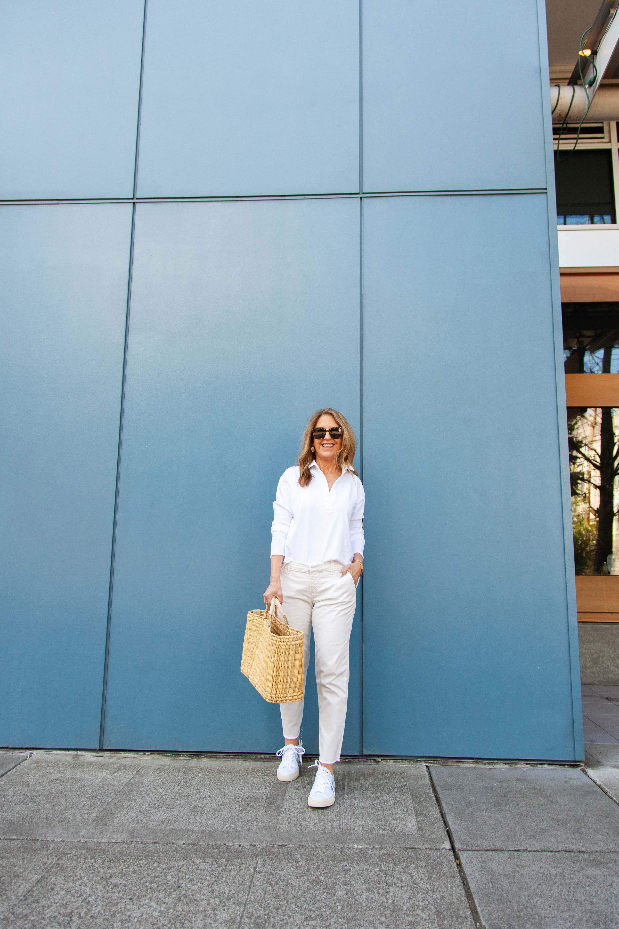 Um estilista Nordstrom vestindo um botão branco, jeans branco e tênis brancos.