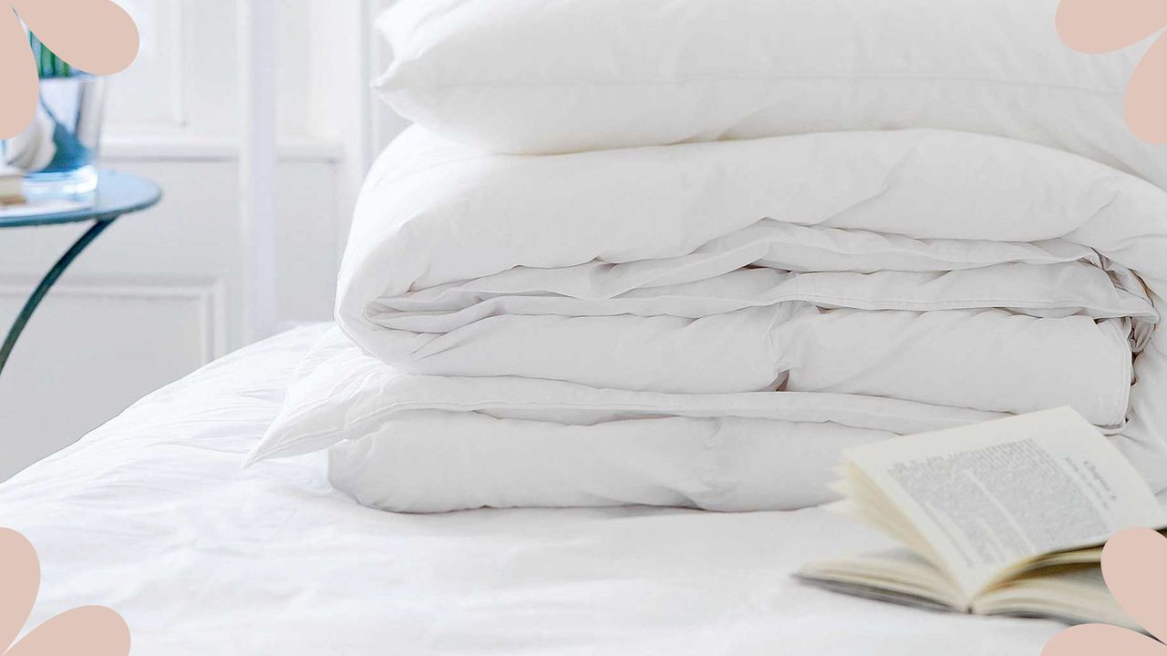 Bed with fresh sheets and duvet in a pile to support an article for how often should you wash your mattress protector