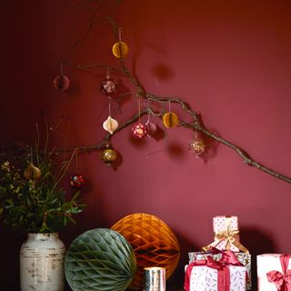 Red wall with branch hung with Christmas decorations