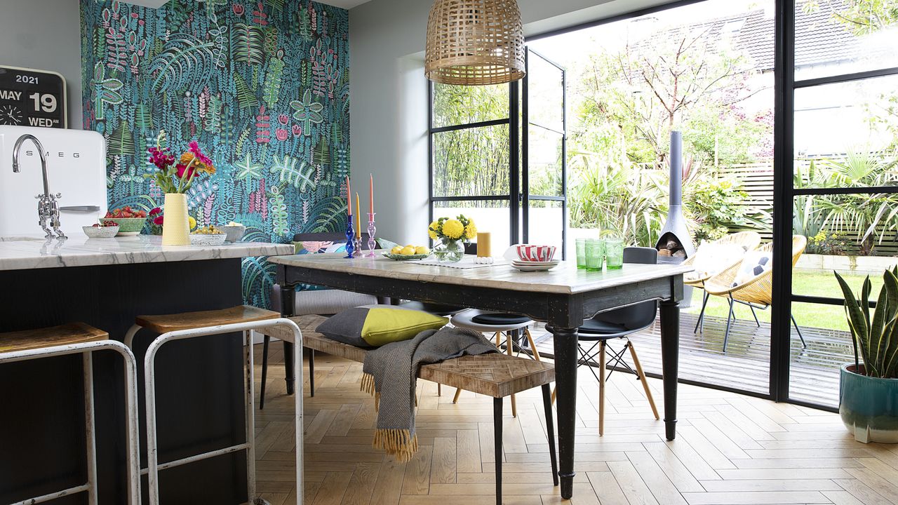 Kitchen-diner with blue/green pattern wallpaper, herringbone floor, farmhouse table and bench, Crittall-style doors