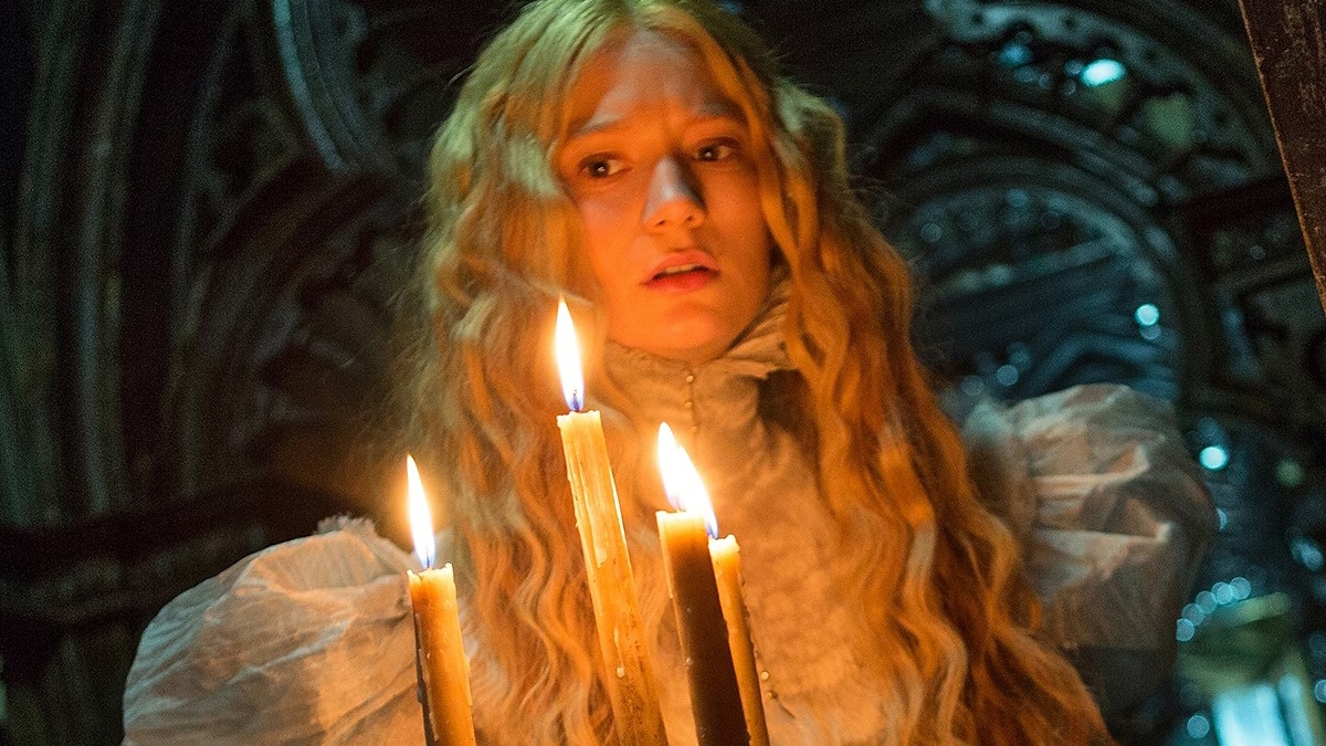 Mia Wasikowska holds candles in a gothic mansion in Crimson Peak
