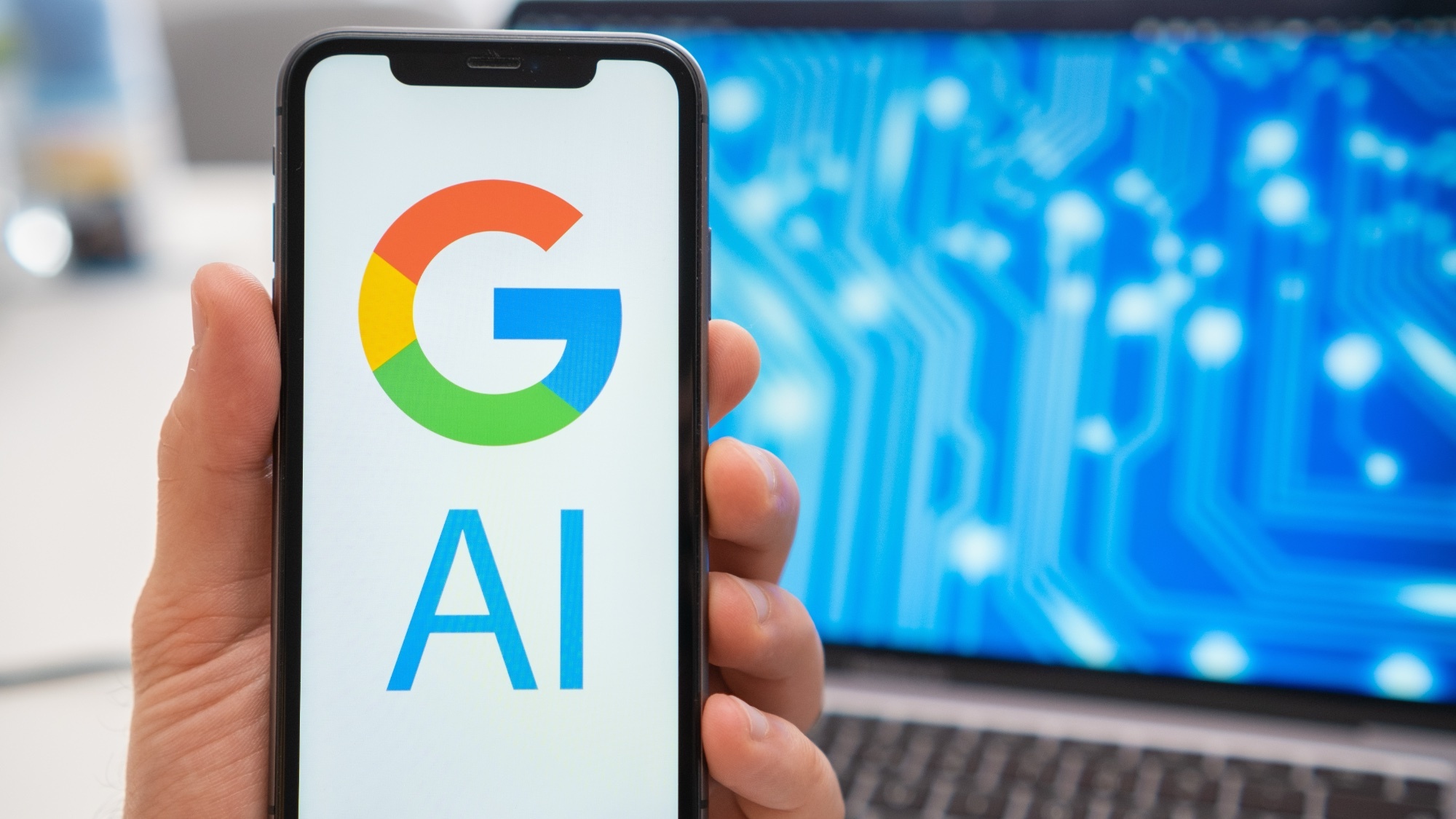 Google AI on phone with laptop in background