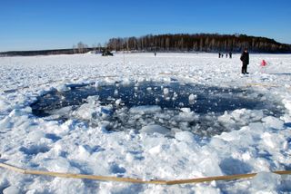A hole, thought to be made by the fragment of the meteor in the ice of Chebarkul Lake is seen on February 16, 2013 some 80 kilometers from Chelyabinsk, Russia. Local government reported more than 1,100 people injured, mostly by flying glass broken by the shock wave of the meteor explosion.