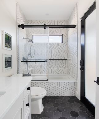 Monochrome bathroom with geometric tiled flooring and black fittings,