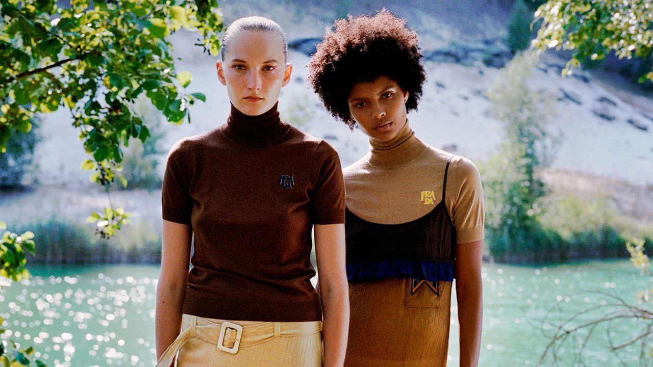 One women wearing a brown Prada tops and skirt and one woman wearing a brown Prada dress standing in front of a lake