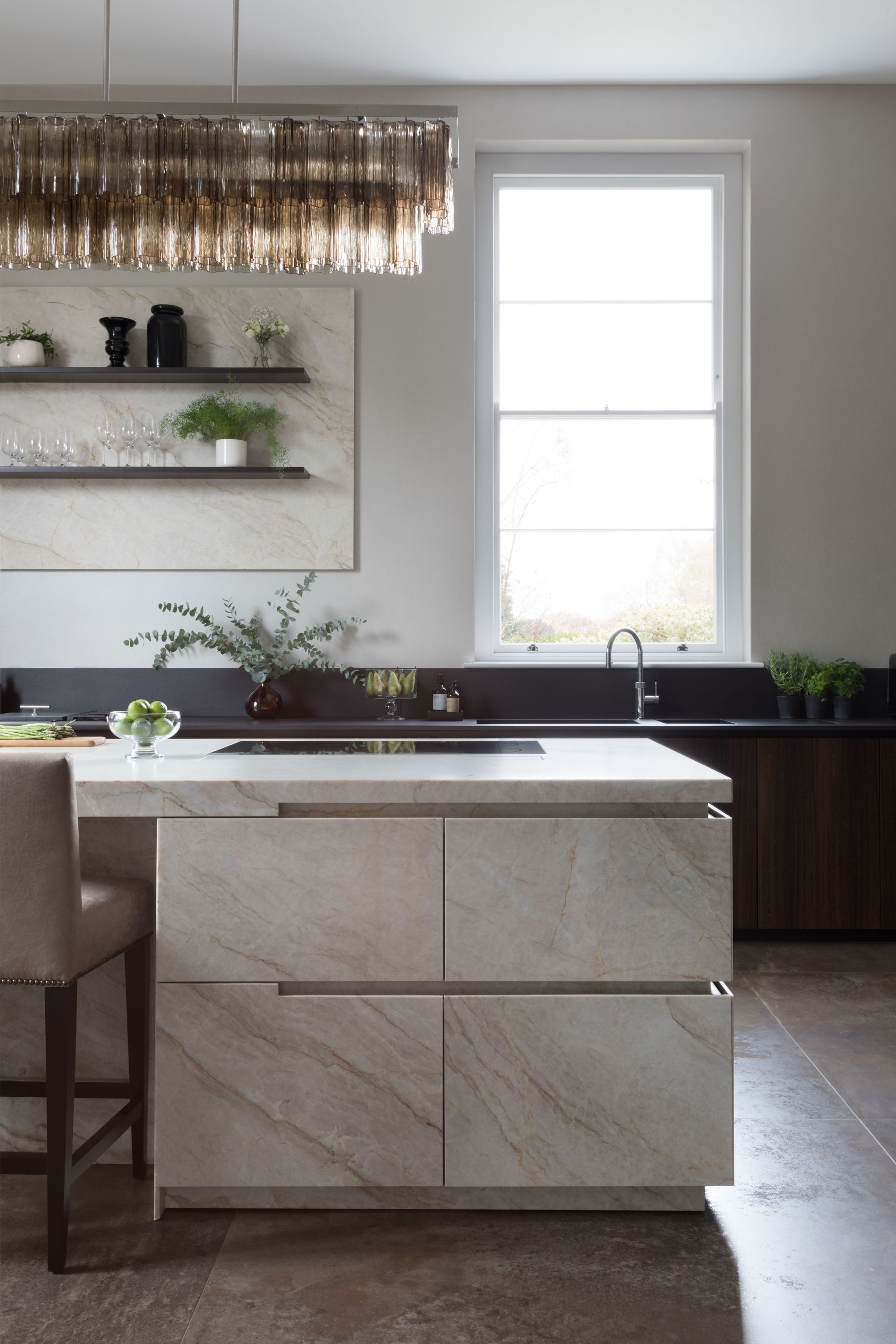 Kitchen with marble look islands and black cabinets and pendant light