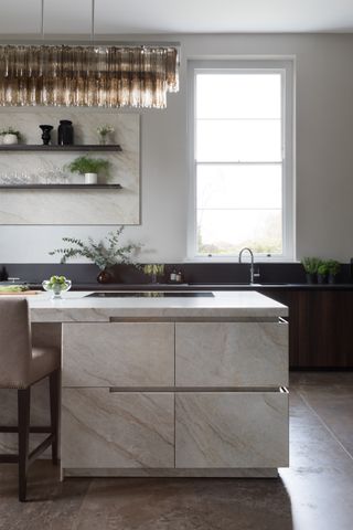 Kitchen with marble look islands and black cabinets and pendant light
