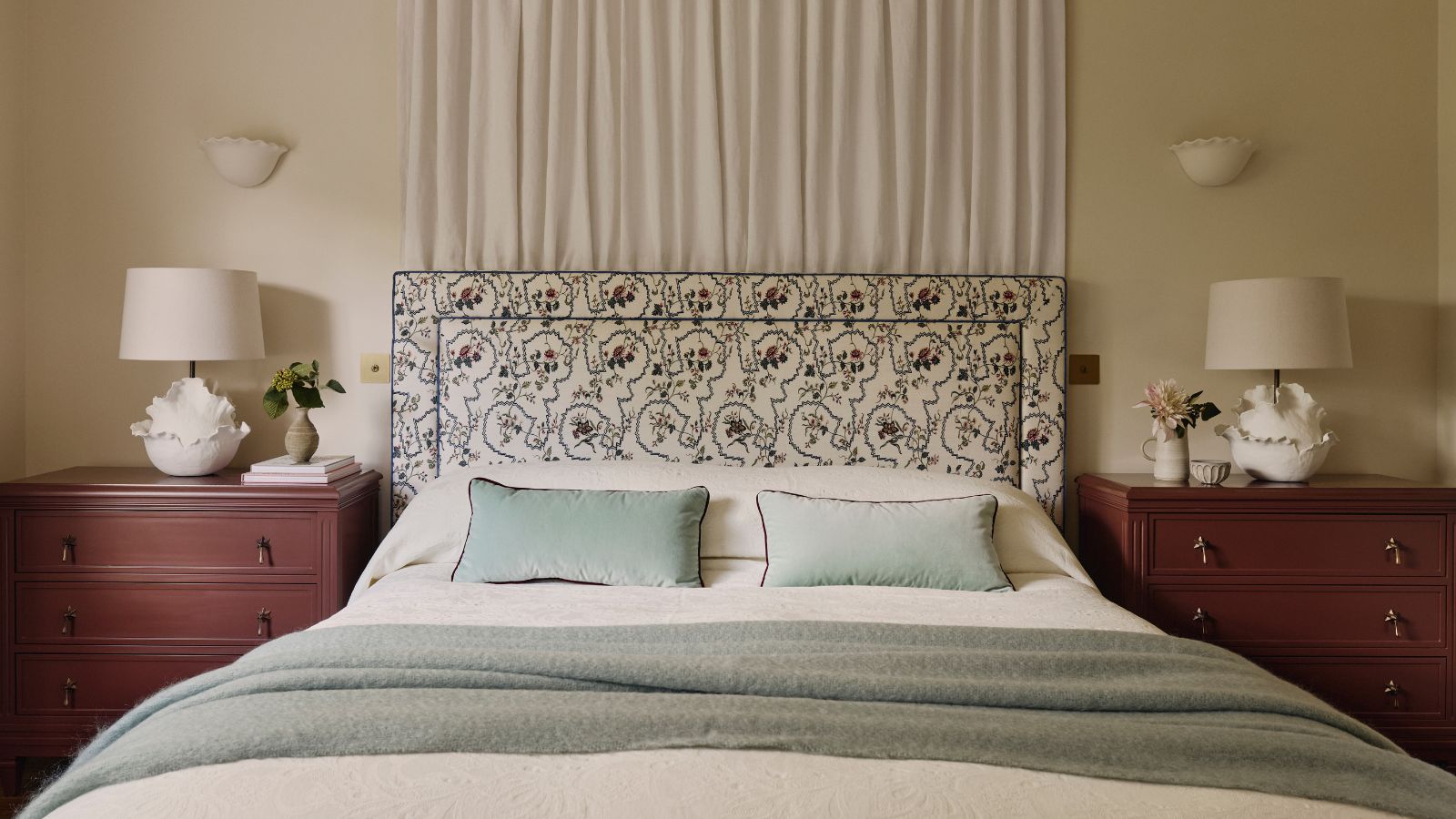 neutral modern meets traditional bedroom with a bed canopy, floral tapestry headboard and two large nightstands painted in a rich red chocolate brown color