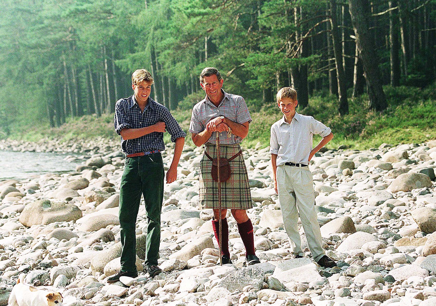 Prince William, King Charles and Prince Harry standing on the rocky beach by the river at Balmoral