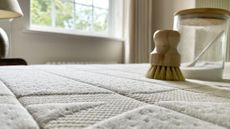 Neutral bedroom with mattress and cleaning products to show How to clean a mattress with baking soda