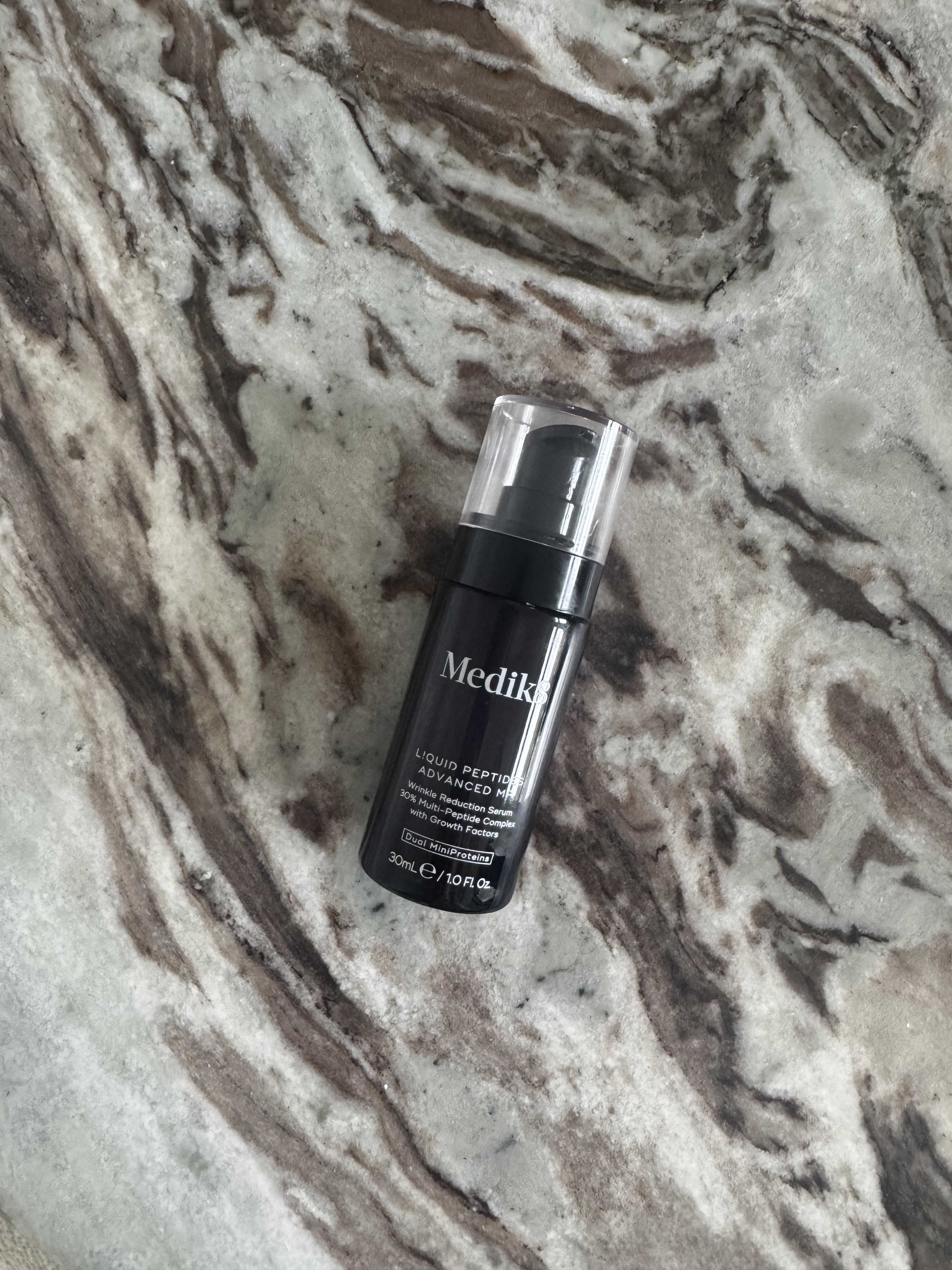 A photo of Medik8 Liquid Peptide Advanced MP Serum on a marble table