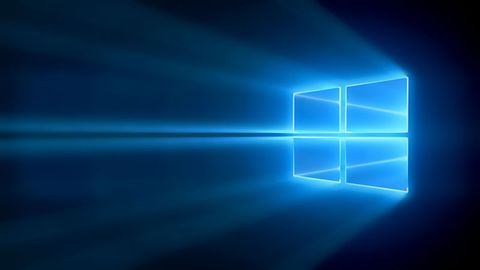 The Microsoft Windows logo with lights shining through on top of a dark background