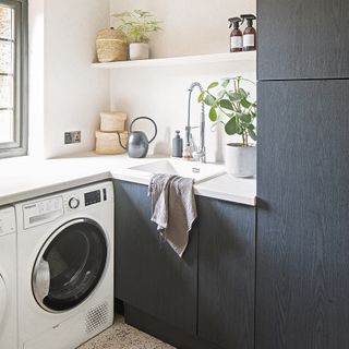 Utility room with washing machine, sink and storage