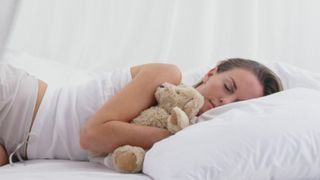 woman in bed cuddling a teddy bear
