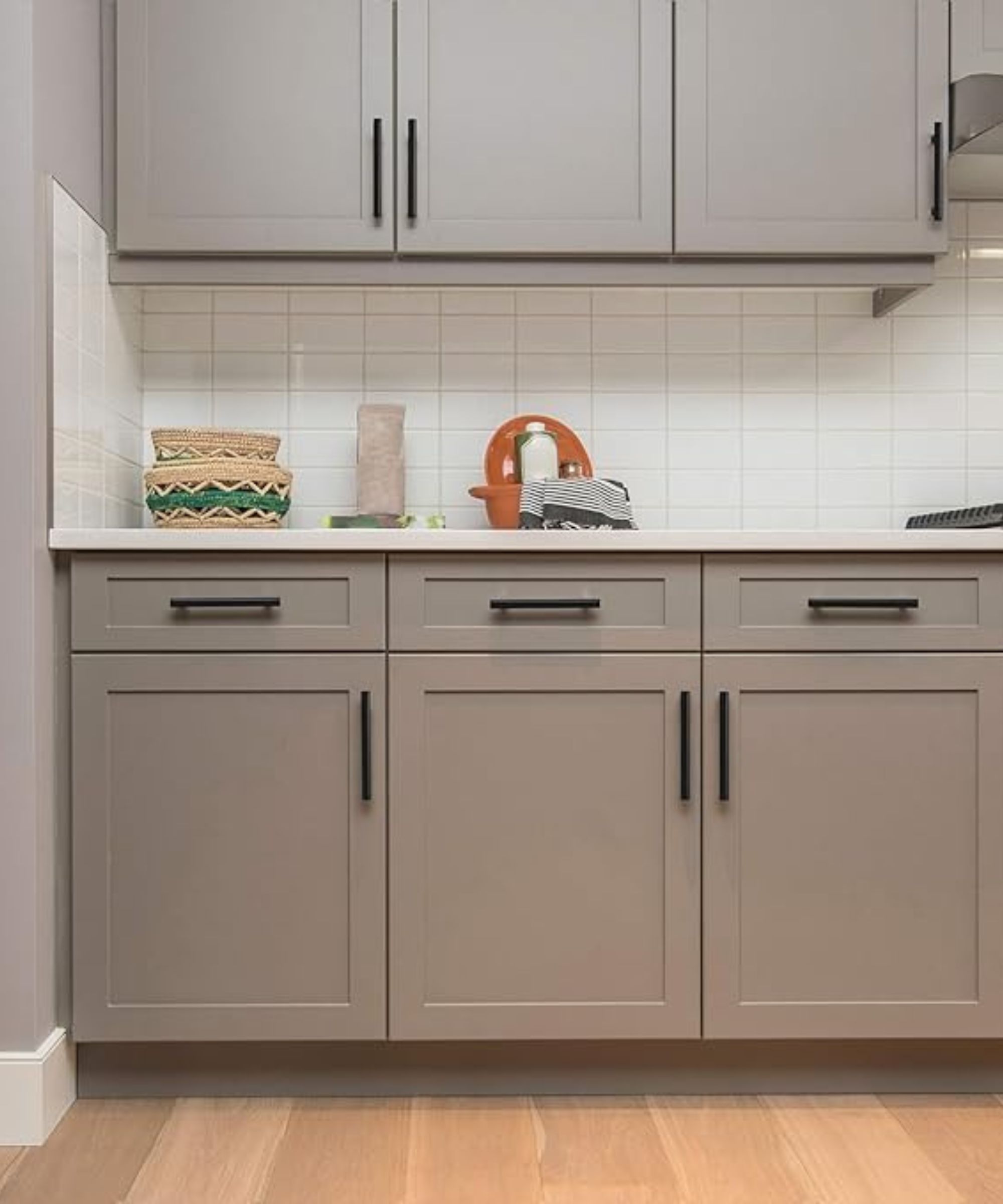 Gray kitchen cabinets with matte black hardware and white countertops