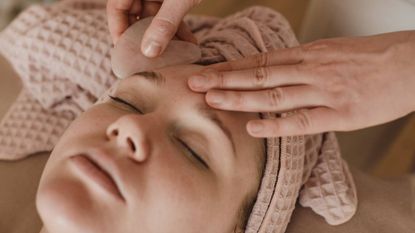 Face yoga, woman relaxing at a spa while someone massages her face