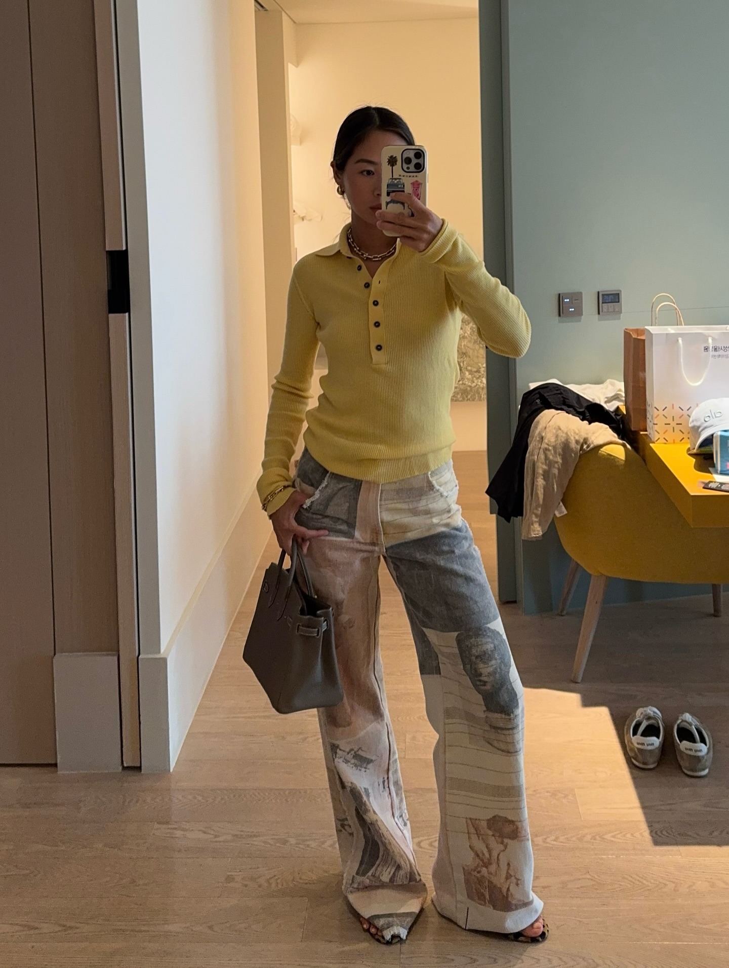 Influencer Aimee Song wearing a yellow polo sweater and printed jeans