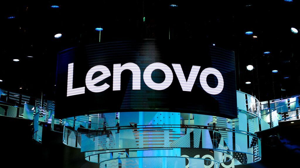 A large Lenovo sign suspended above a dimly lit conference floor