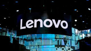 A large Lenovo sign suspended above a dimly lit conference floor