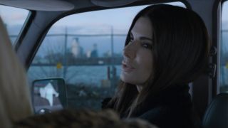 Sandra Bullock sitting in the passenger seat of a car looking to her left.