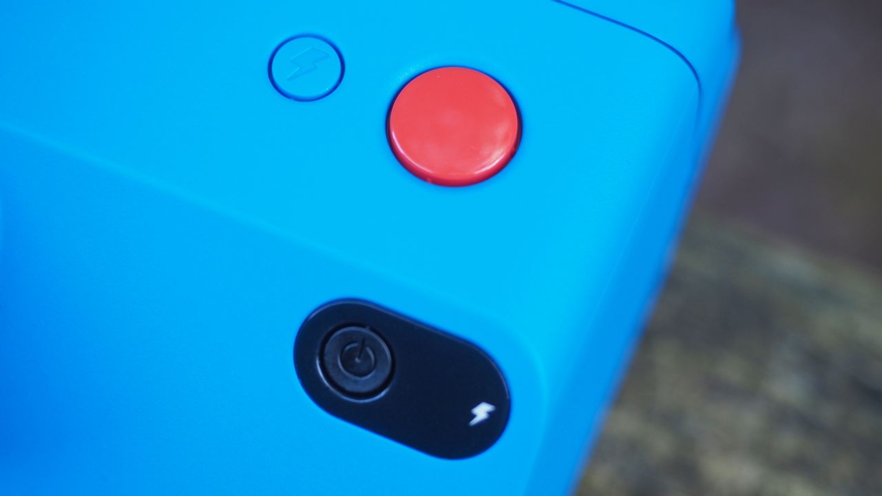 Blue Polaroid Go Gen 2 camera, on a wooden surface in a woodland setting