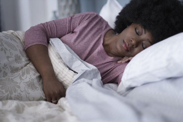 How a pillow could alleviate your pain: woman sleeping in bed with pillow