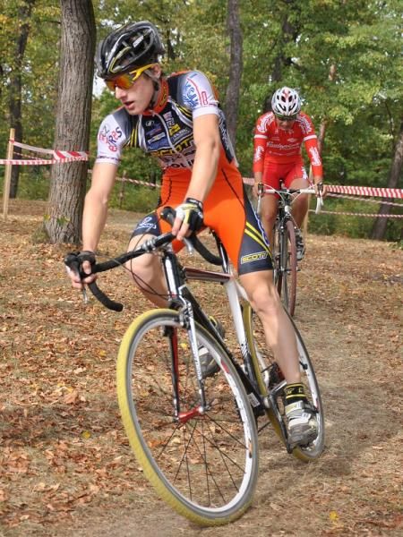 The junior men ride through a forest.