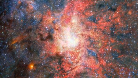 This image features data from Webb&rsquo;s MIRI (Mid Infrared Instrument) to capture the most detailed mid-infrared view yet of the field that hosts the highly evolved star IRS 3, which is located just 0.55 light-years from Sagittarius A*, the Milky Way galaxy's central supermassive black hole.&nbsp; An international team of astronomers have discovered that dust and water can form and survive surprisingly close to this supermassive black hole. The observations reveal that the evolved star IRS 3 continues to enrich its surroundings with newly formed material despite the intense radiation environment around Sagittarius A*. [Image description: A bright, densely populated star cluster lies near the centre of the image, surrounded by intricate clouds of glowing gas and dust in shades of red, pink, orange, and blue. Dark lanes of dust weave through the nebula, contrasting with the luminous central region. Countless stars are scattered across the field, with a few brighter foreground stars showing Webb's characteristic diffraction spikes. An irregular black region occupies the lower-right corner of the image, indicating an area where no observational data was available.]