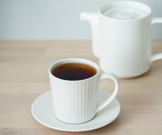 teacup and kettle on a wooden countertop