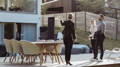 Real estate agent showing new property to couple outdoors