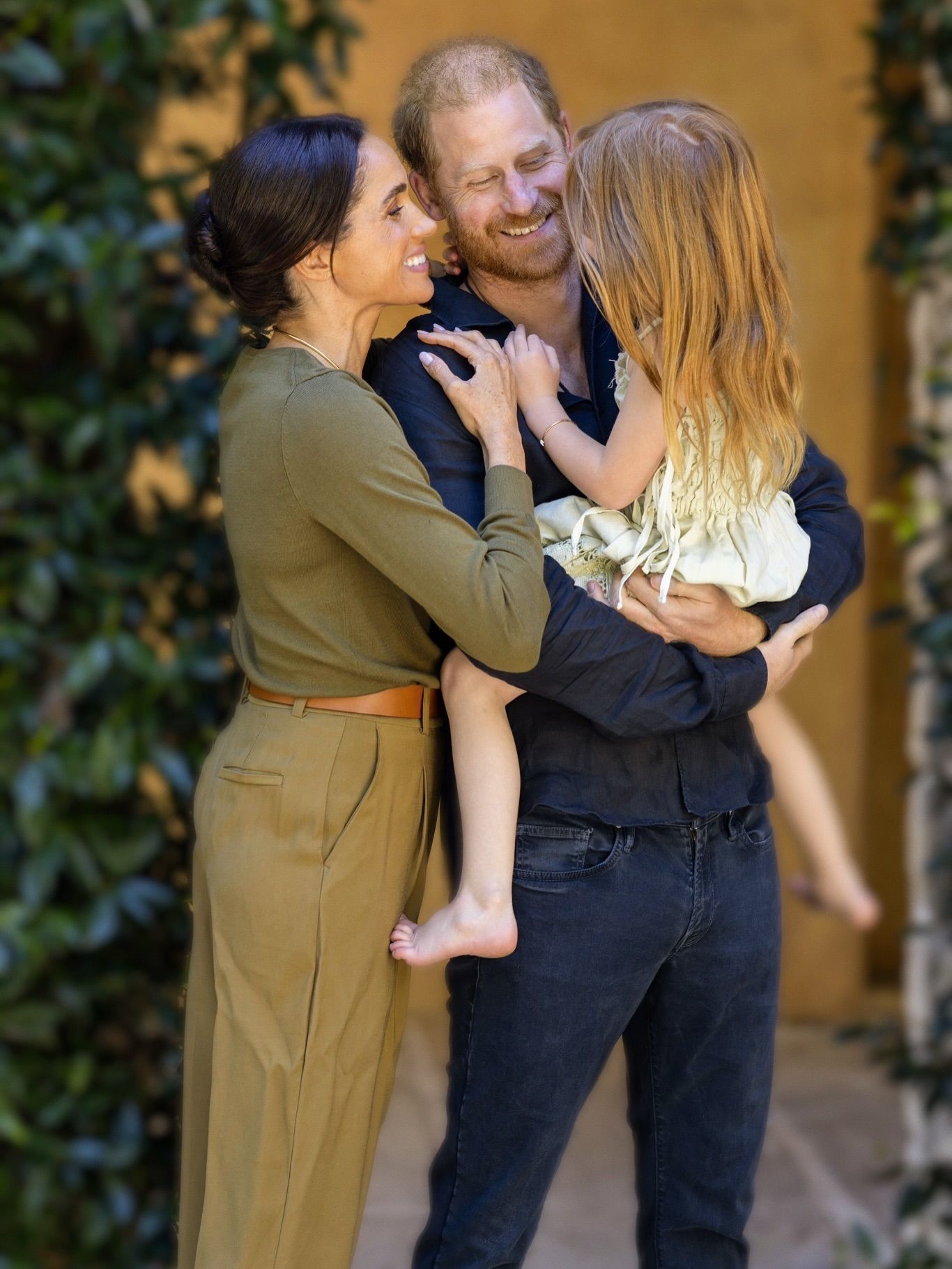 Meghan Markle hugging Prince Harry, holding Princess Lilibet