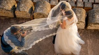 Wedding photographer photographs couple from beneath the bride's veil