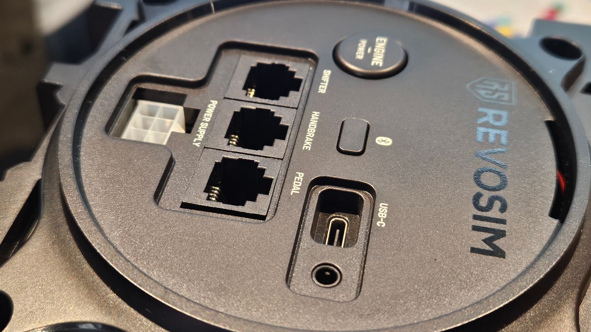 The back of the Nacon Revosim Pure racing wheel base unplugged, showing how the wires connect to one another, displayed at Big Ben Week 2025 (photographed by Future)