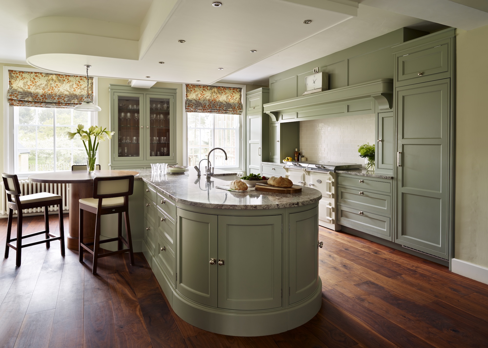 a sage green kitchen with a curved kitchen island that also has extra storage